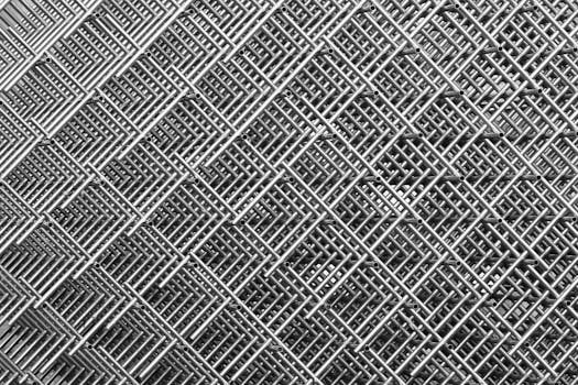 Abstract close-up of interwoven metal grids creating a symmetrical, textured pattern in monochrome.