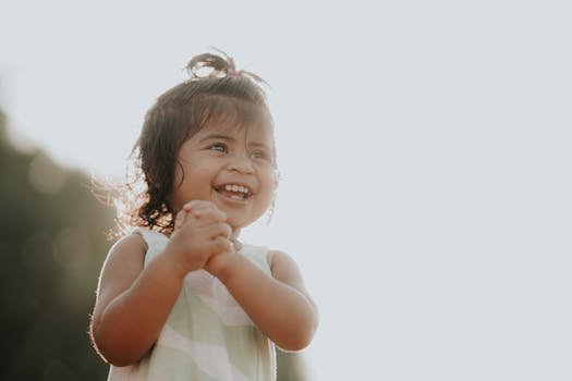 Adorable toddler smiling brightly outdoors in sunlight, depicting pure joy and innocence.
