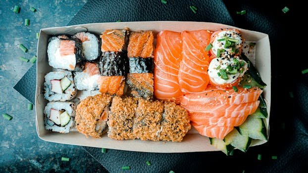 A vibrant box of sushi and sashimi featuring salmon and tuna, perfect for food lovers.