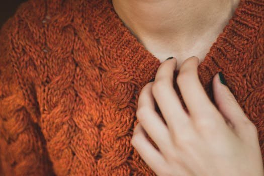 close-up van hand die een oranje gebreide trui aanraakt