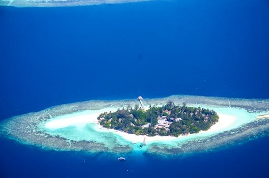 A stunning aerial view of a tropical island resort in the Maldives surrounded by azure waters and coral reefs.